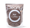 Clearly Not Coffee powder in a container with a scoop, showing the product label and a spoonful of the powder on a white background.